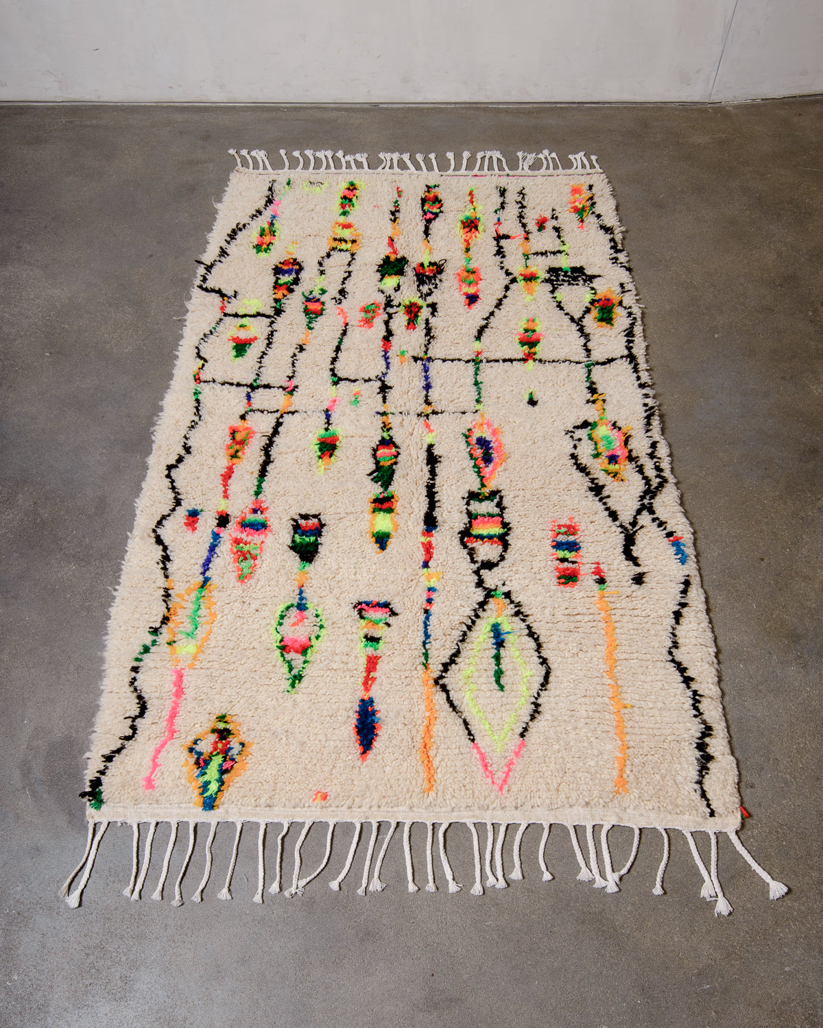 Berberlin Azilal rug made of sheep’s wool and neon cotton laying flat on concrete floor.